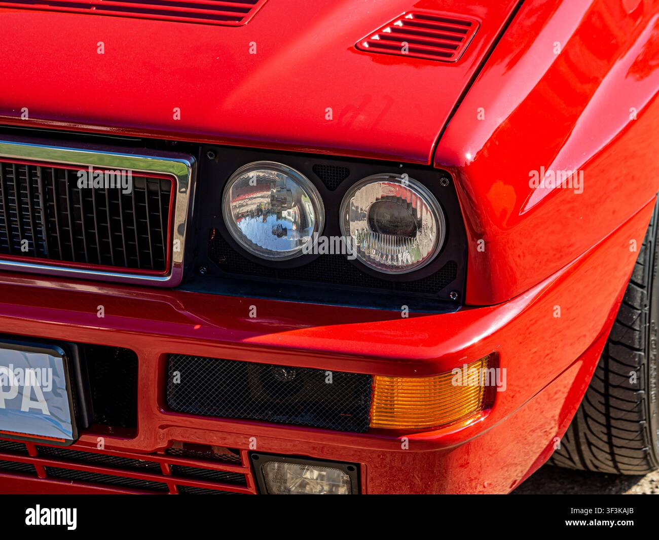 Primo piano della parte anteriore di un'auto sportiva italiana vintage rossa con doppi fari rotondi e griglia cromata Foto Stock