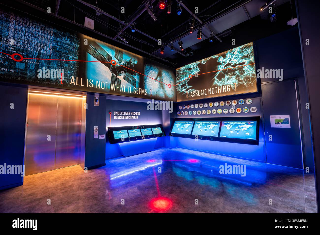 Debriefing interattivo della missione allo Spy Museum | WASHINGTON D.C., Stati Uniti — Una galleria interattiva allo Spy Museum internazionale permette ai visitatori di toccare schermi sensibili per verificare una missione di spionaggio sotto copertura, incorniciata da testi murali che recitano “Assume Nothing” e “All Is Not What It Seems”. I badge visualizzati sopra gli schermi rappresentano vere agenzie di intelligence da tutto il mondo, un accenno ai principi del mestiere che l’esposizione è stata creata per insegnare. Foto Stock