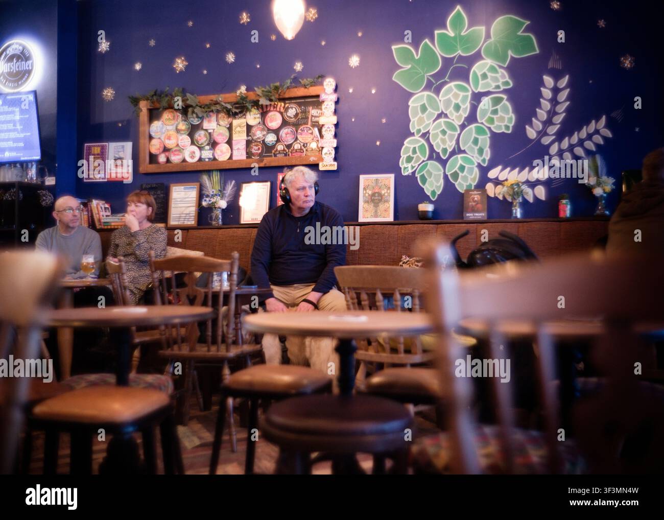 Uomo con cuffie in un ambiente da pub Foto Stock