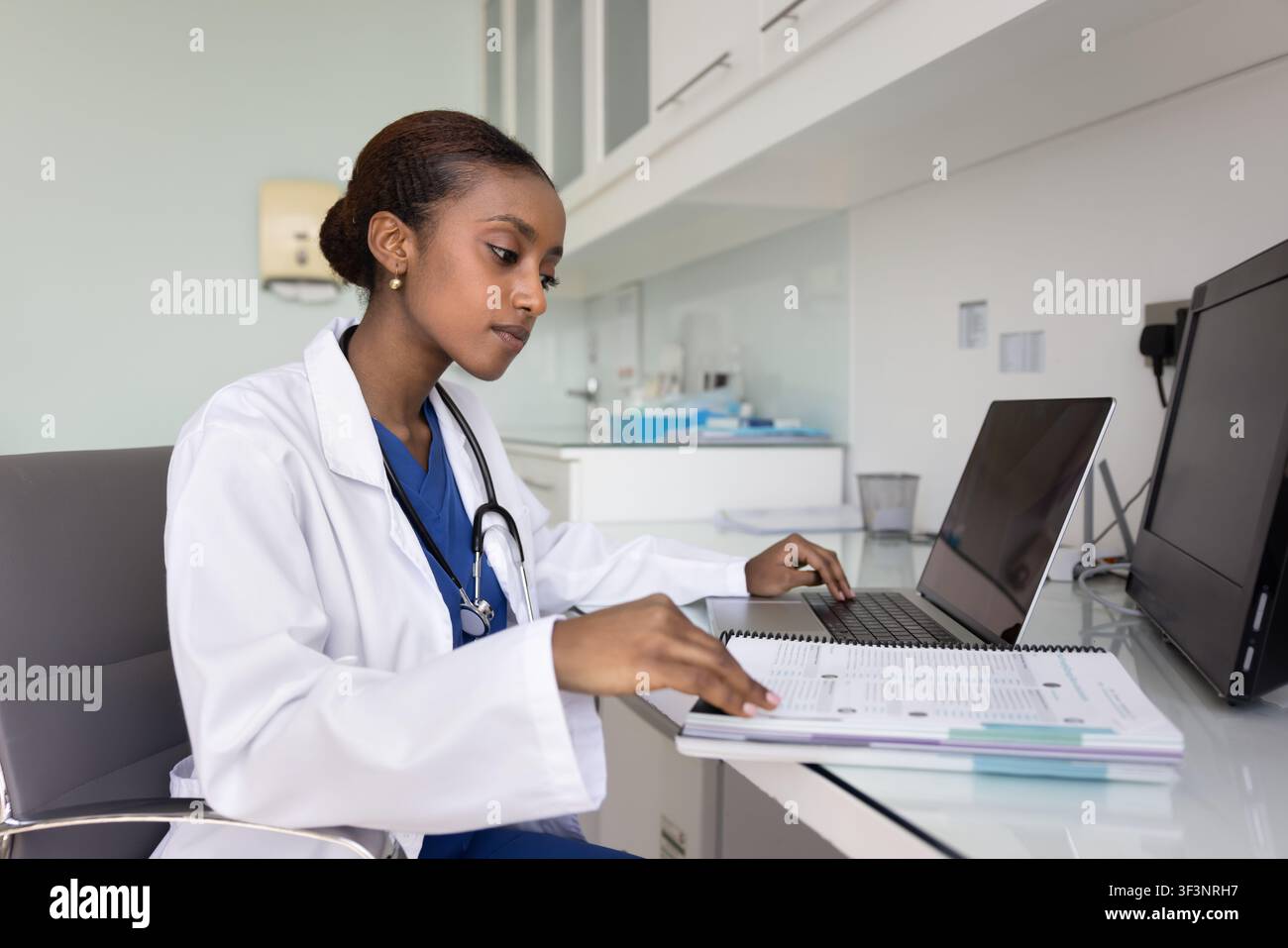 Giovane internista afroamericana concentrata che fa ricerca Foto Stock