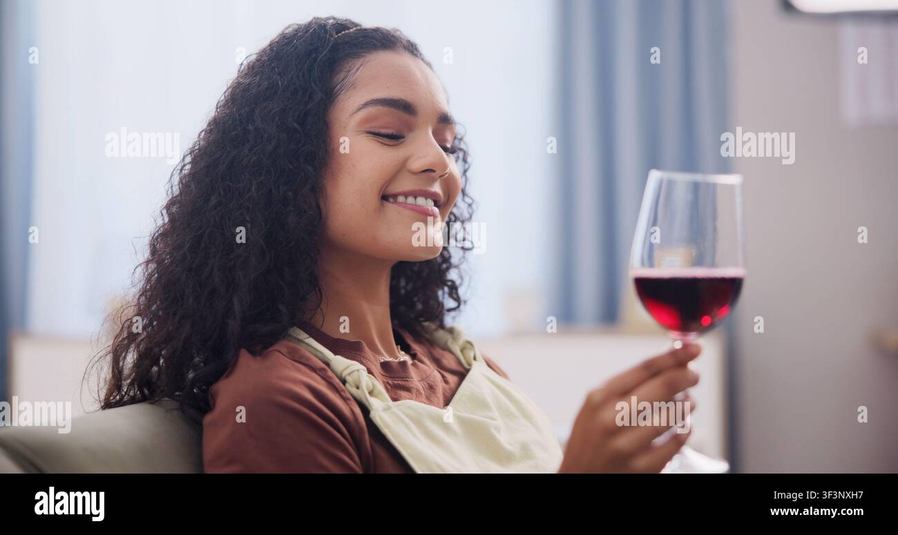 Pausa, gusto e vino con donna felice sul divano nel soggiorno di casa per il test di una bevanda fatta in casa. Bicchiere, relax e sorriso con una persona che beve alcolici Foto Stock