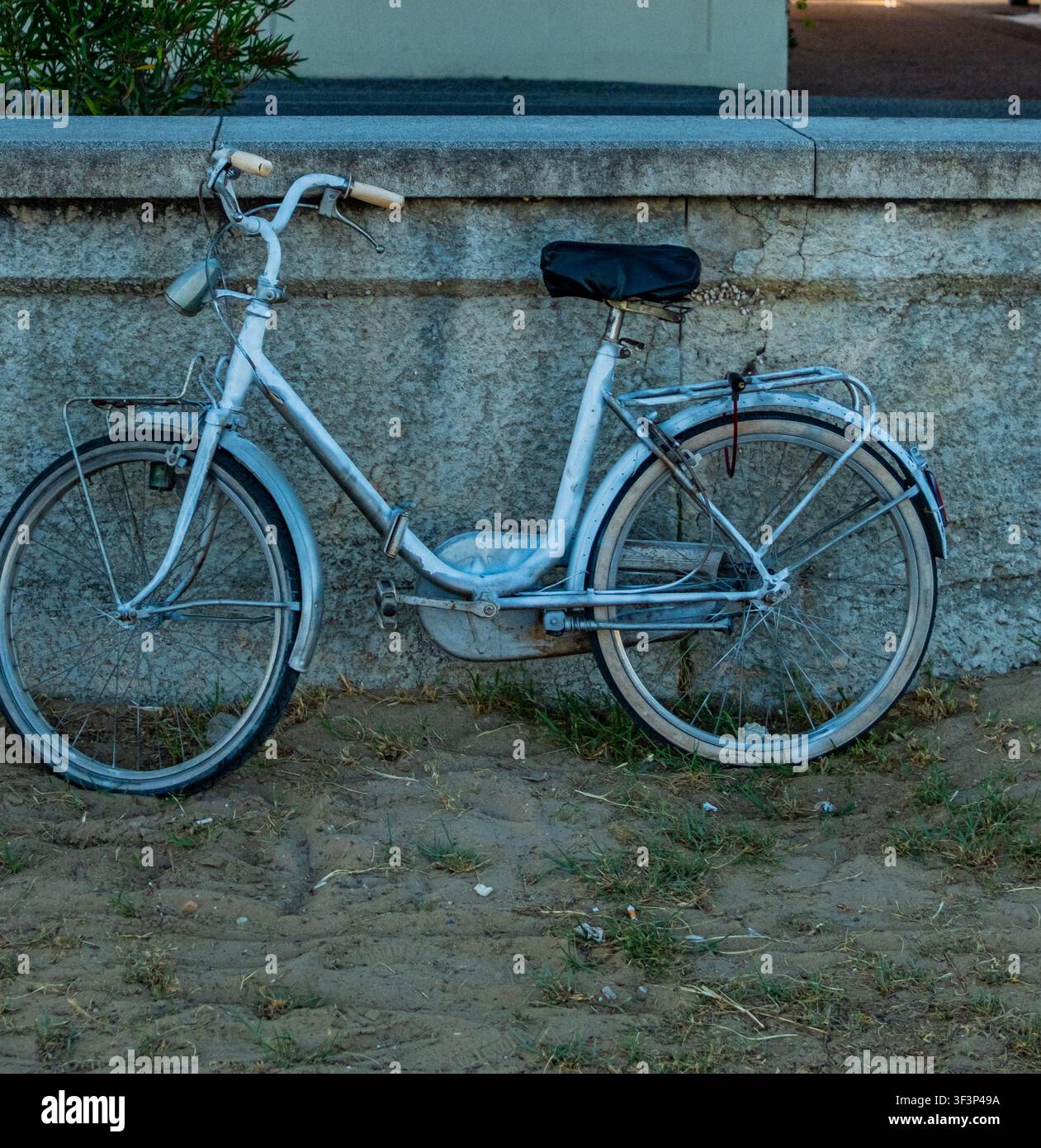Bicicletta bianca vintage appoggiata a un muro di pietra nell'Italia settentrionale Foto Stock