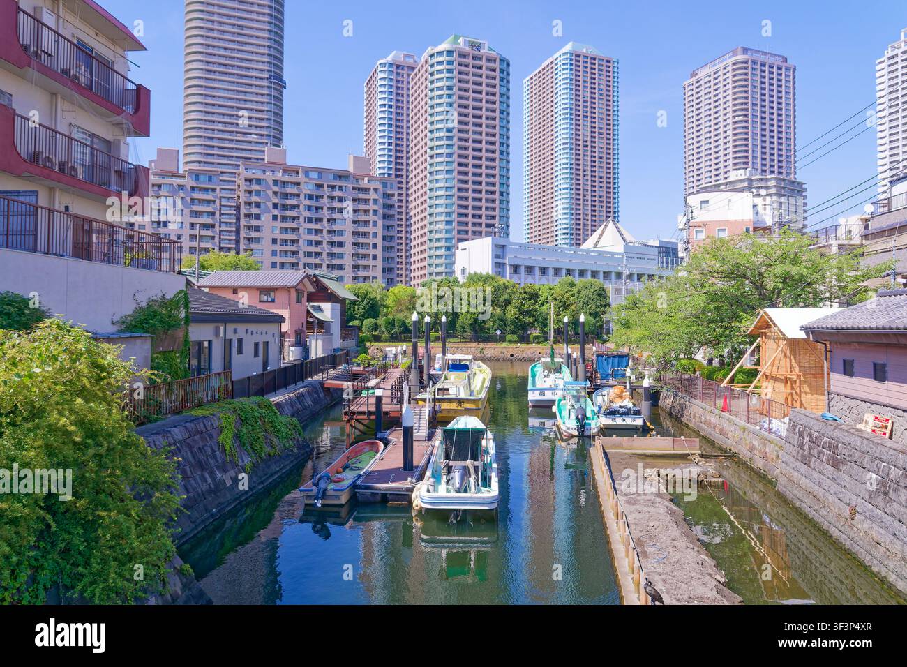 Canale storico di Tokyo, Giappone, fiancheggiato da case tradizionali per barche e moderni grattacieli residenziali a Tsukishima, un paesaggio unico sul lungomare dove Edo ancora Foto Stock
