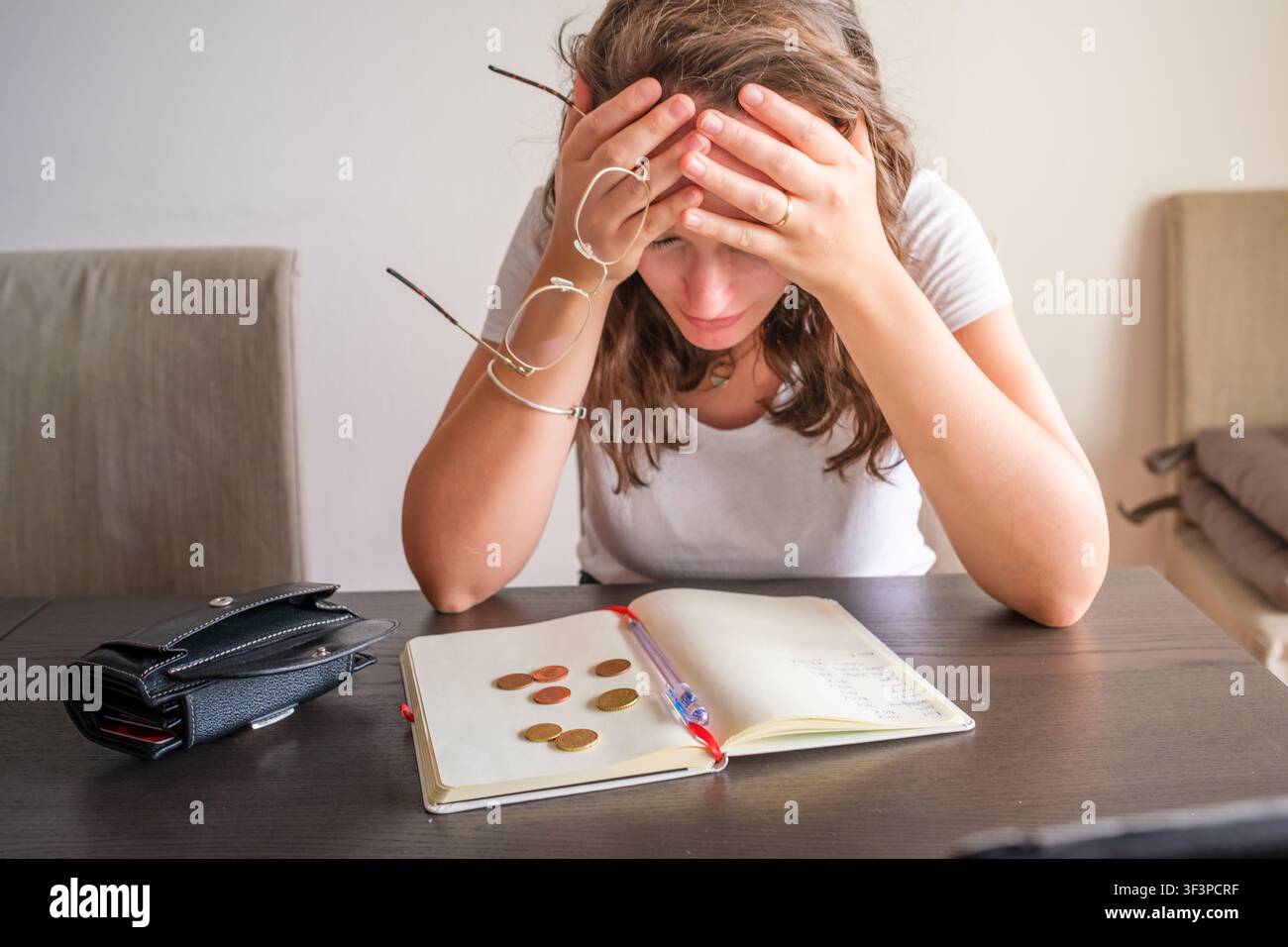 Donna che lotta con problemi finanziari a casa, conta monete, si sente stressata e ha mal di testa Foto Stock