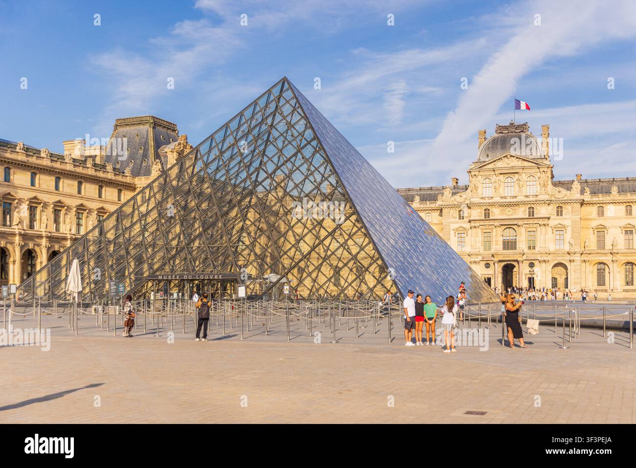 PARIGI, FRANCIA - 25 LUGLIO 2026: Iconica piramide di vetro e facciata storica del palazzo del Museo del Louvre Foto Stock