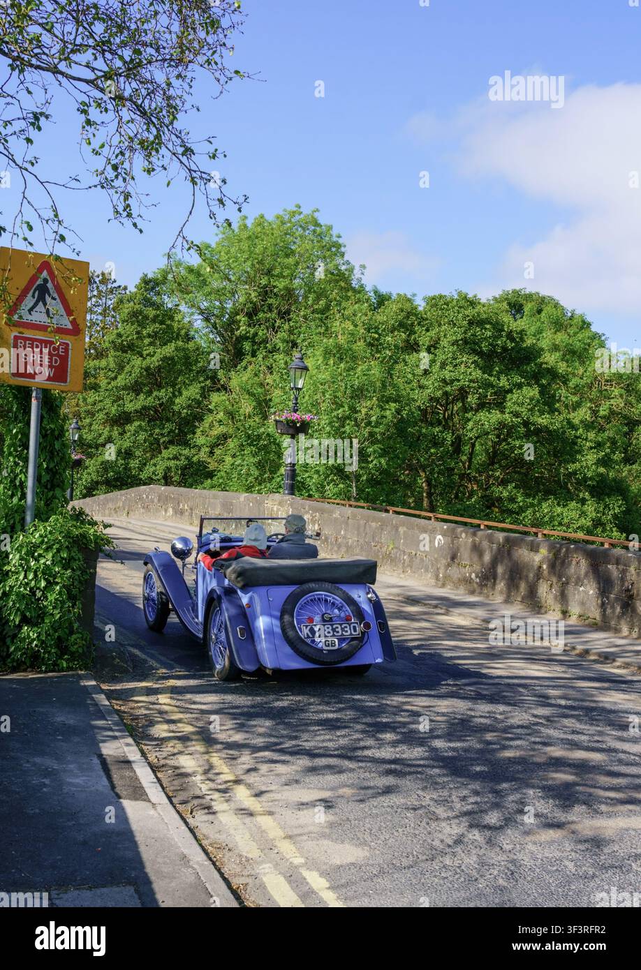 Una MG decappottabile vintage blu chiaro attraversa il ponte storico di Pateley Bridge, Nidderdale, North Yorkshire, Inghilterra, in una luminosa giornata estiva. Foto Stock