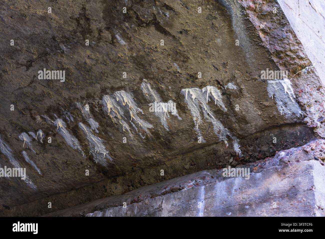 stalattiti antropogeniche all'interno di un tunnel di cemento scuro Foto Stock