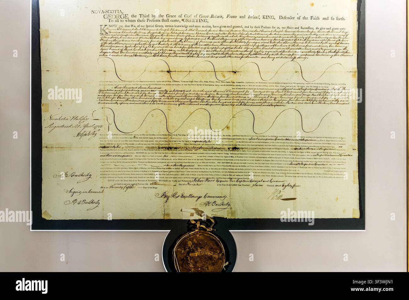 Un documento storico di concessione di terre risalente al regno di re Giorgio III del Regno Unito, munito di sigillo di cera e firme, è in mostra al Centre de recherche père Clarence-d’Entremont sulla Route 335 a West Pubnico. Il documento fa parte della collezione genealogica del centro di ricerca, dedicato alla storia della famiglia acadiana e dell’insediamento della regione. Argyle Municipal, Nuova Scozia, Canada Foto Stock