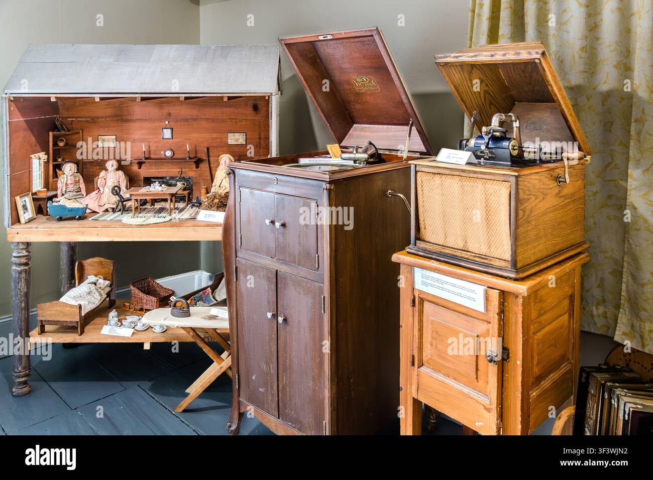 Una casa delle bambole con mobili in miniatura si trova accanto a due grammofoni vintage in una vetrina al Musée des Acadiens des Pubnicos sulla Route 335 a West Pubnico, Nova Scotia. Gli oggetti fanno parte della collezione del museo sulla cultura quotidiana acadiana dell'inizio del XX secolo. Argyle Municipal, Nova Scotia, Canada Foto Stock