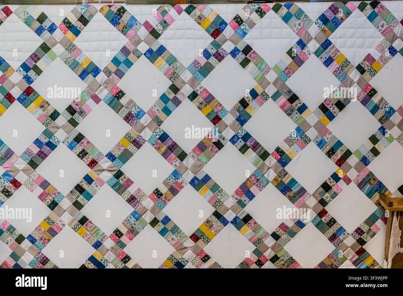 Una coperta patchwork fatta a mano con pannelli bianchi a forma di diamante e quadrati di stoffa colorati è in mostra al Musée des Acadiens des Pubnicos sulla Route 335 a West Pubnico, Nuova Scozia. Le coperte cucite a mano fanno parte della tradizione artigianale acadiana e sono anche in vendita nel negozio del museo adiacente. Argyle Municipal, Nuova Scozia, Canada Foto Stock