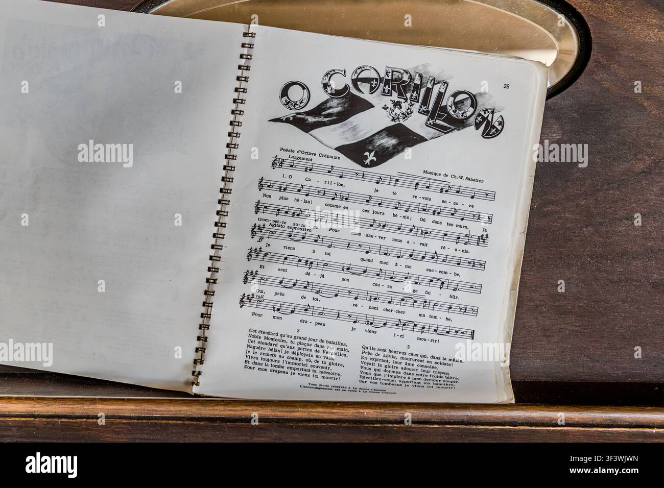 Un libro di canzoni aperto contenente la canzone "Ô Carillon" si trova in un edificio storico del Villaggio Storico Acadico della Nuova Scozia su Old Church Road a Lower West Pubnico, Nuova Scozia. Il testo è stato scritto dal poeta del Quebec Octave Crémazie, e la melodia è stata composta da Ch. W. Sabattier – la canzone celebra la bandiera storica del Carillon come un simbolo precoce dell'identità franco-canadese. Argyle Municipal, Nuova Scozia, Canada Foto Stock