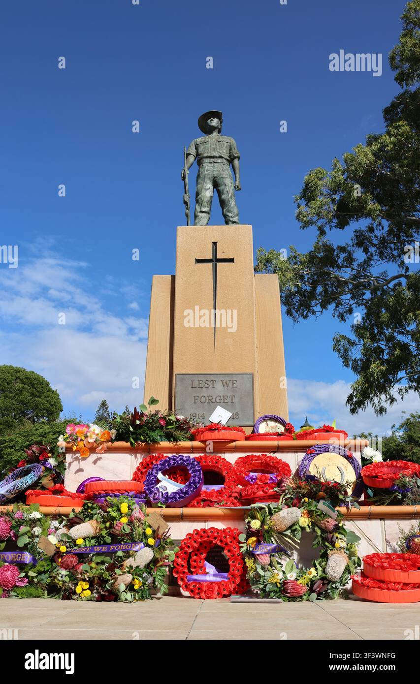 Omaggi floreali luminosi e ghirlande ammassati alla base della statua del monumento funebre della Guerra di Gladstone Anzac Park, Queensland, Australia Foto Stock