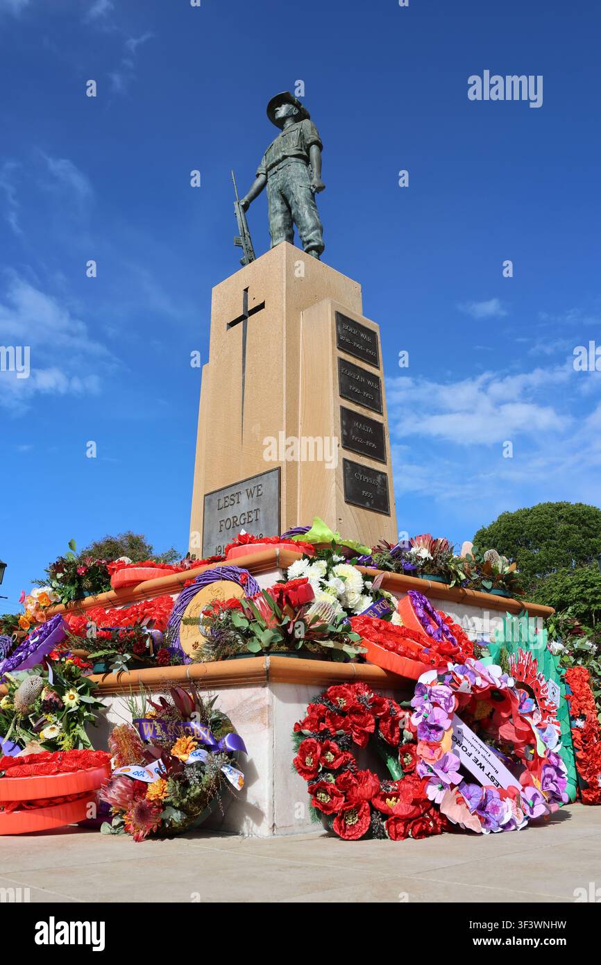 Vista angolata della statua del monumento funebre della Guerra di Gladstone Anzac Park con vivaci ghirlande commemorative alla base, Queensland, Australia Foto Stock