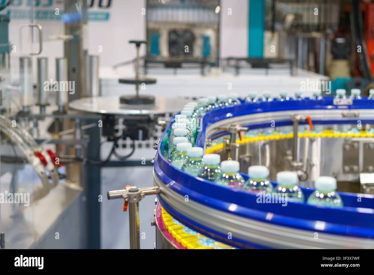 Centinaia di bottiglie di plastica trasparente piene di acqua potabile fresca che si muovono su un nastro trasportatore curvo su una linea di produzione automatizzata all'interno di un moderno Foto Stock
