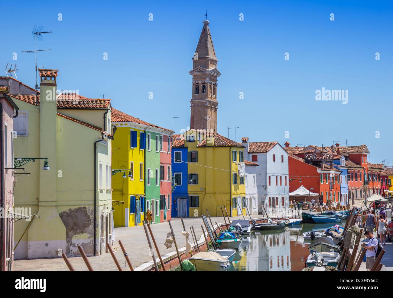 Torre di mattoni inclinata storica in una vivace strada del canale a Burano, Venezia, Italia Foto Stock