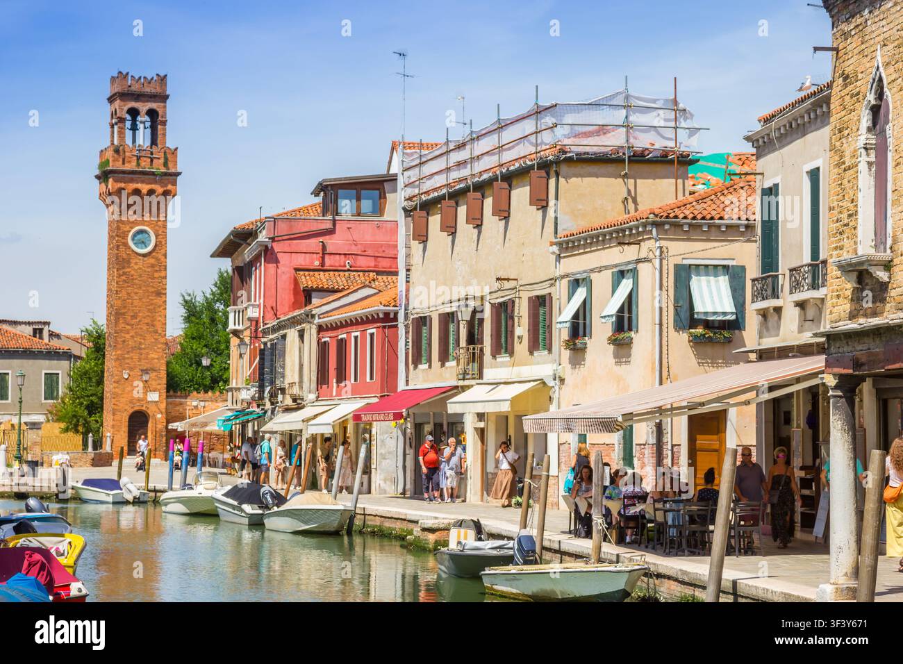 Torre dell'orologio storico in mattoni su un canale a Murano, Venezia, Italia Foto Stock