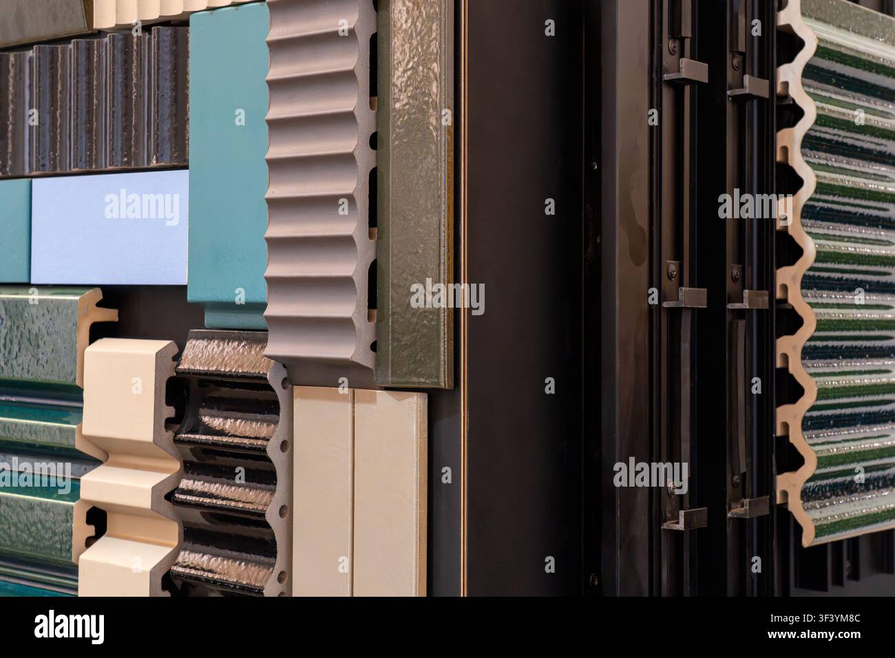Campioni assortiti di profilati per rivestimenti e piastrelle con colori turchesi beige e neri, primo piano di un catalogo di materiali da costruzione Foto Stock