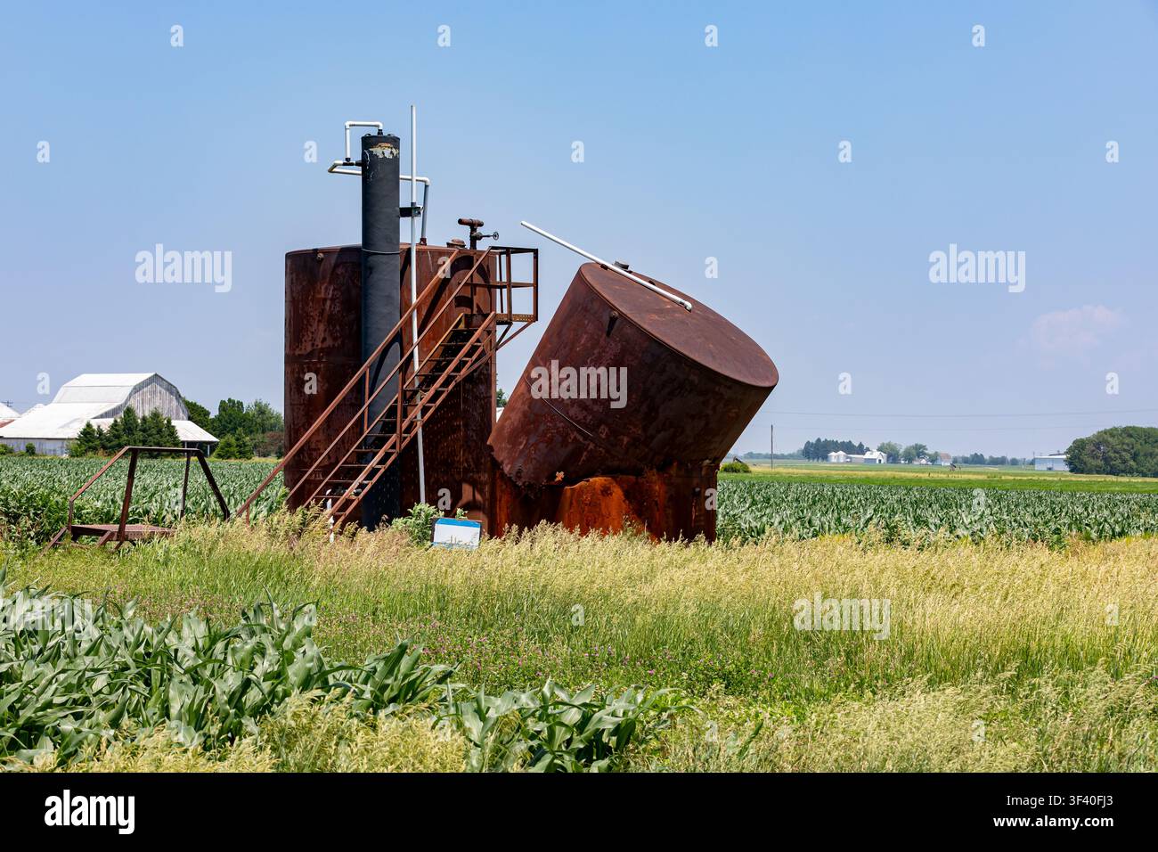 Vecchi serbatoi di stoccaggio di pozzi petroliferi che collassano in un campo agricolo. Abbandono di pozzi petroliferi, inquinamento ambientale e concetto di produzione di petrolio Foto Stock