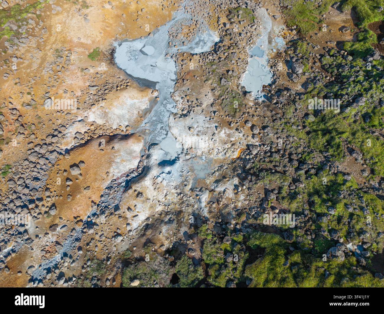 Vista aerea dall'alto di piscine di fango geotermiche, depositi minerali, roccia vulcanica e vegetazione verde che formano motivi naturali in Islanda. Foto Stock
