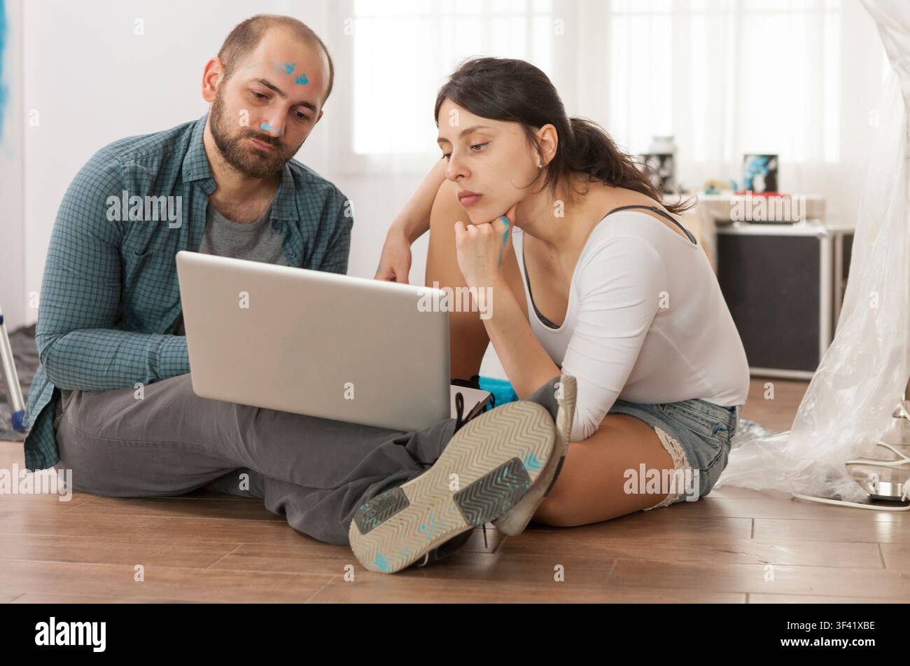 Coppia sposata che fa acquisti online per attrezzi per la ristrutturazione durante la ristrutturazione dell'appartamento, mostrando rulli per vernici, lavori di riparazione e miglioramento degli interni in un pratico restyling della casa. Foto Stock
