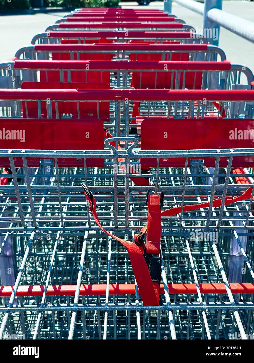 Prima piano di carrelli della spesa vuoti con maniglie rosse nel parcheggio di un supermercato Foto Stock