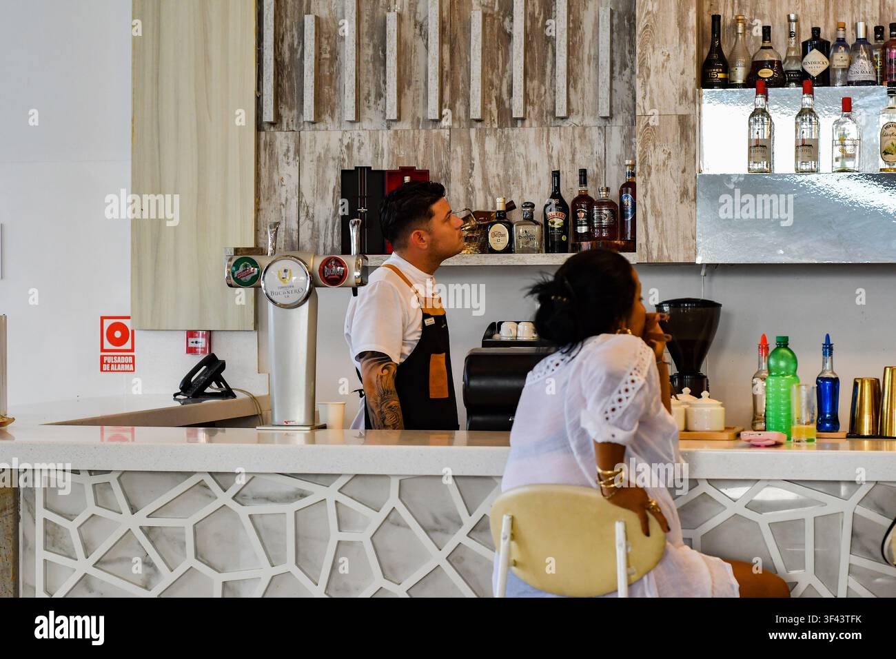 Barista che prepara bevande dietro un bancone moderno mentre un ospite è seduto al bar del resort Melia Trinidad Peninsula, Trinidad, Cuba - luglio 2026 Foto Stock