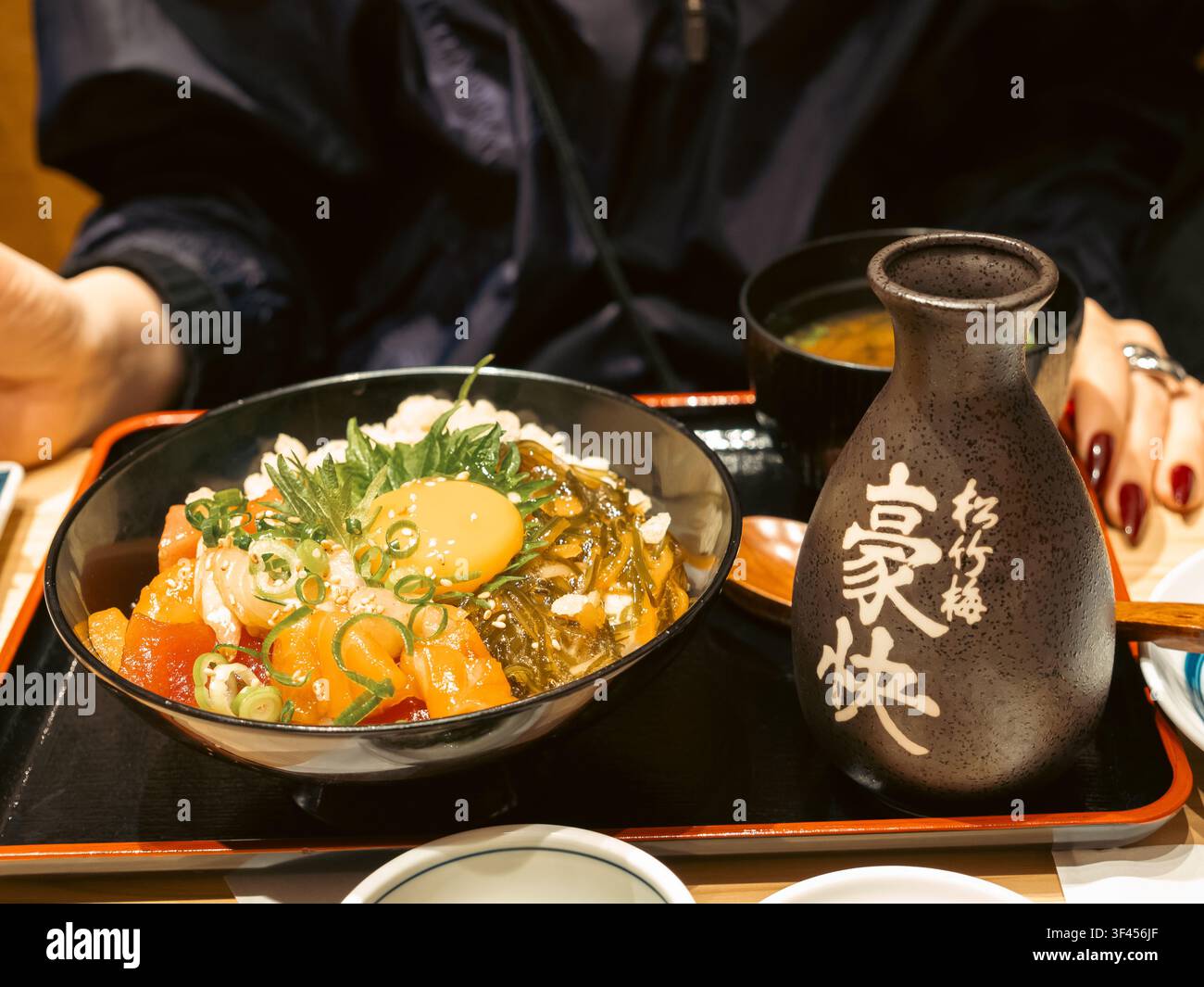 Ciotola di riso Kaisendon con tonno crudo, salmone e tuorlo d'uovo servita con zuppa di miso e una fiaschetta di saké in un ristorante a Shinjuku, Tokyo, Giappone Foto Stock