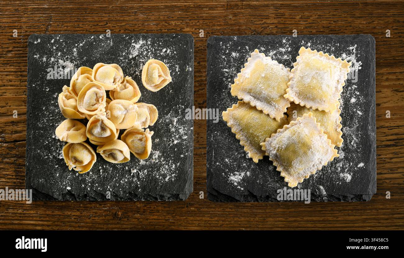 Cappelletti e ravioli italiani freschi su piatti di ardesia, pronti per la cottura Foto Stock