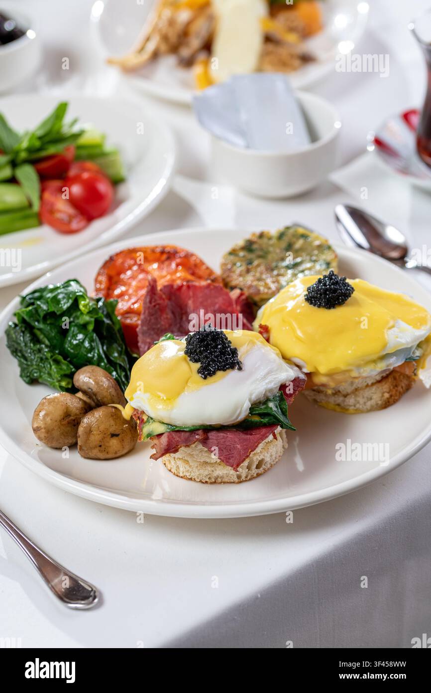 Uova benedette con salmone, spinaci, salsa olandese e caviale nero come guarnizione Foto Stock