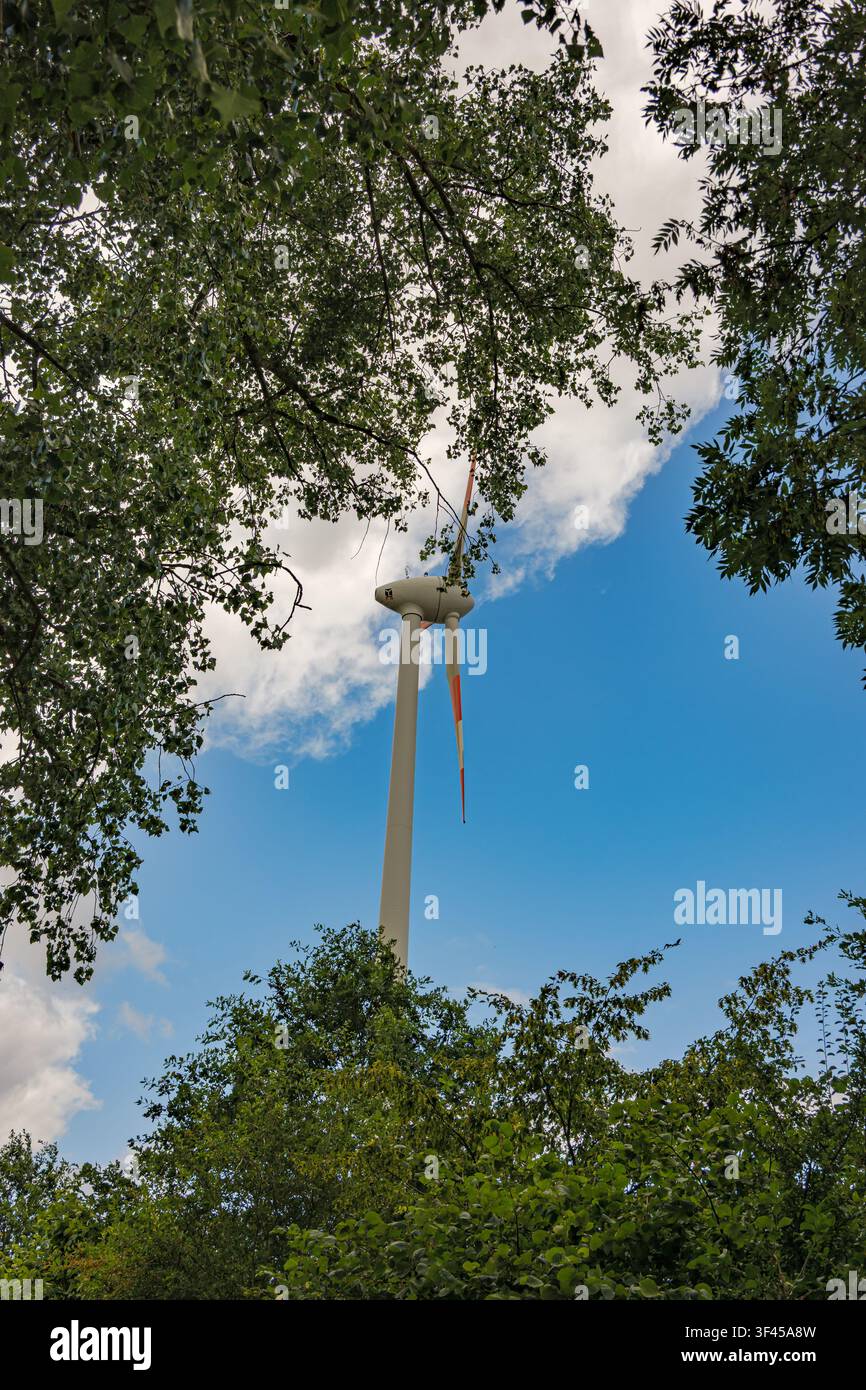 Turbolina moderna incorniciata da alberi decidui verdi sotto un cielo blu nuvoloso a Coesfeld, Germania Foto Stock