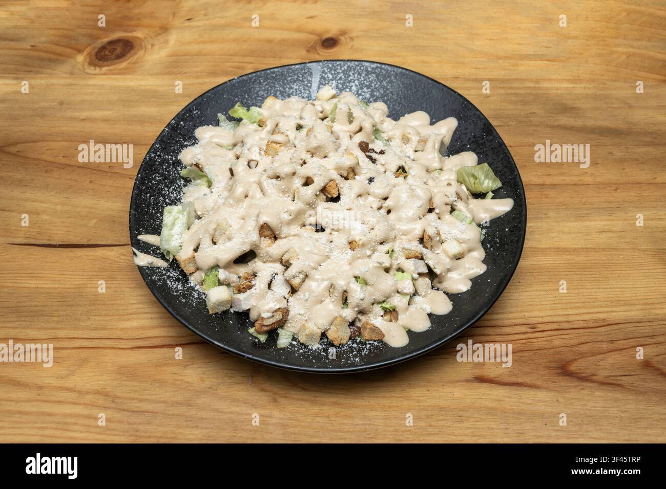 Insalata con noci, crostini e lattuga abbondantemente condita con salsa cremosa e spolverata di formaggio grattugiato Foto Stock