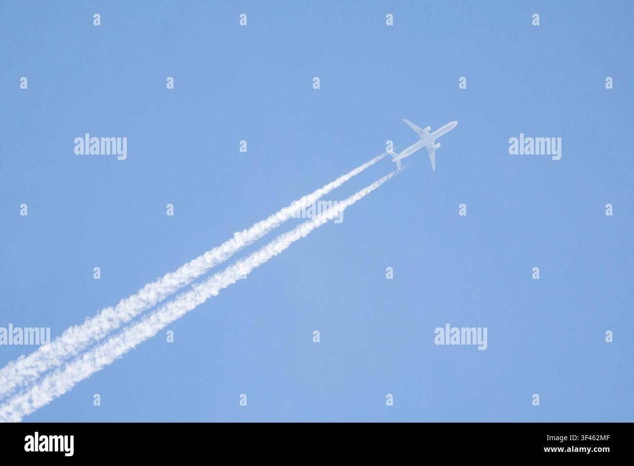 Aereo a reazione che lascia scie di vapore su un cielo blu, Foto Stock