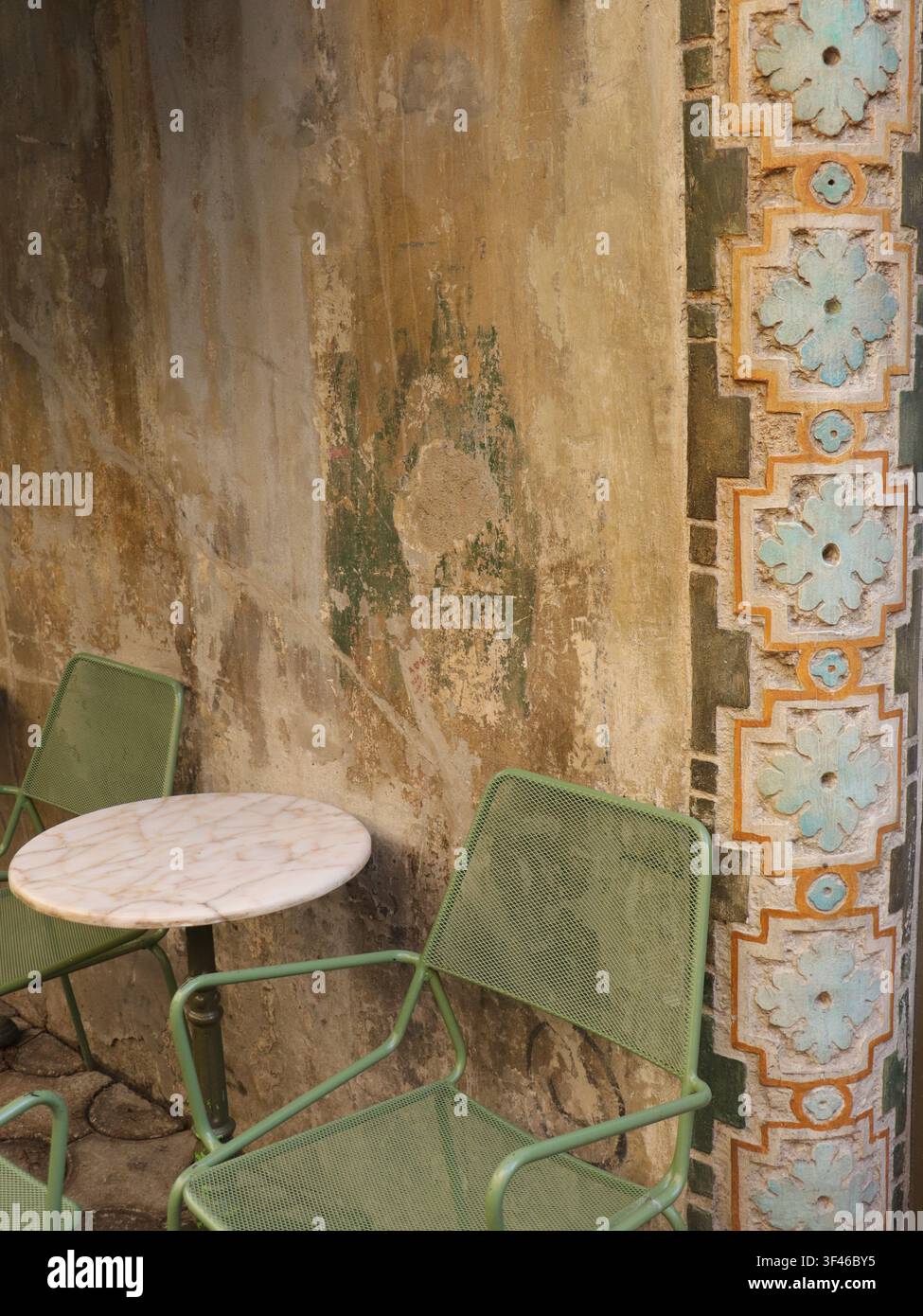 Tavolo da caffè accanto a un muro consumato con vivaci piastrelle art nouveau a Istanbul. Vita lenta in un quartiere bohémien. Foto Stock