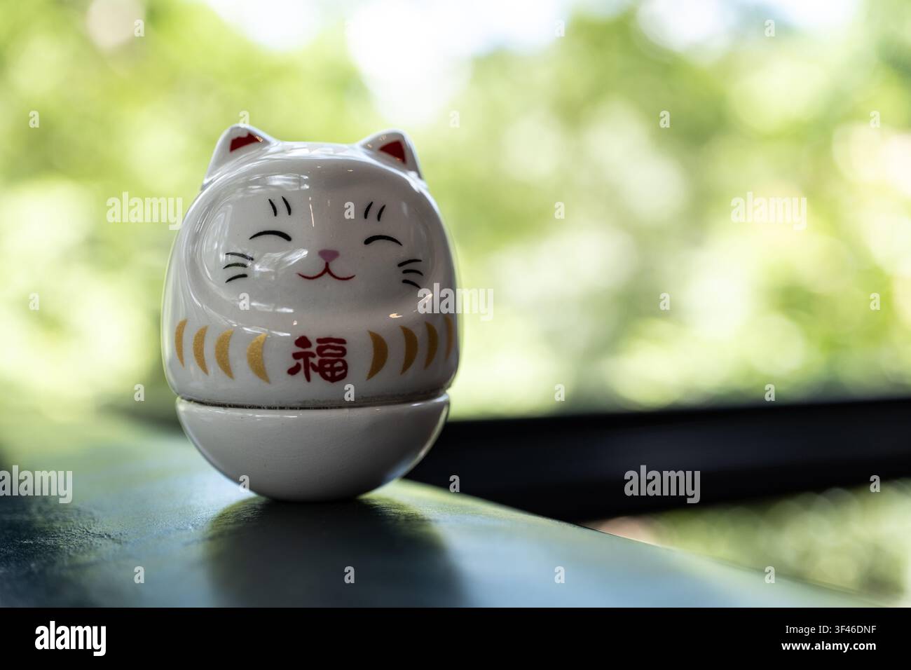 Chiang Mai, Thailandia - 25 luglio 2026: Figurina daruma di gatto bianco con strisce dorate e personaggio Fuku, paesaggio con spazio per copia a destra Foto Stock