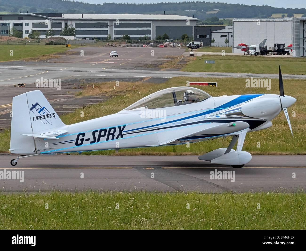 Aereo acrobatico G‑SPRX Firebirds in taxi all'aeroporto di Exeter, UK, con il pilota visibile nella cabina di pilotaggio durante le operazioni a terra. - Immagine stock catturata con smartphone