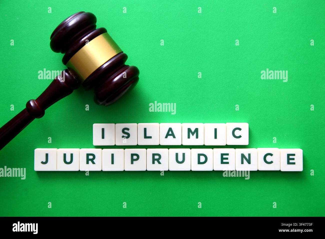 Martelletto e tessere di lettere che compongono la giurisprudenza islamica su uno sfondo verde Foto Stock