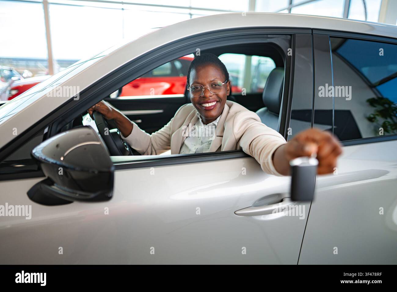 Donna nera felice che mostra la chiave dell'auto all'interno di un veicolo nuovo Foto Stock