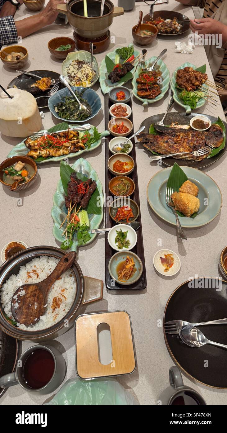 Vista aerea della cucina tradizionale sundanese con nasi liwet, lotek, verdure, riso e contorni assortiti serviti per un pasto comunitario. Foto Stock