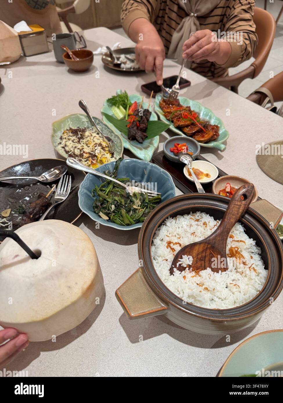 Nasi liwet sundanese tradizionale servito con riso al vapore e contorni assortiti in un contesto di cena comune. Foto Stock