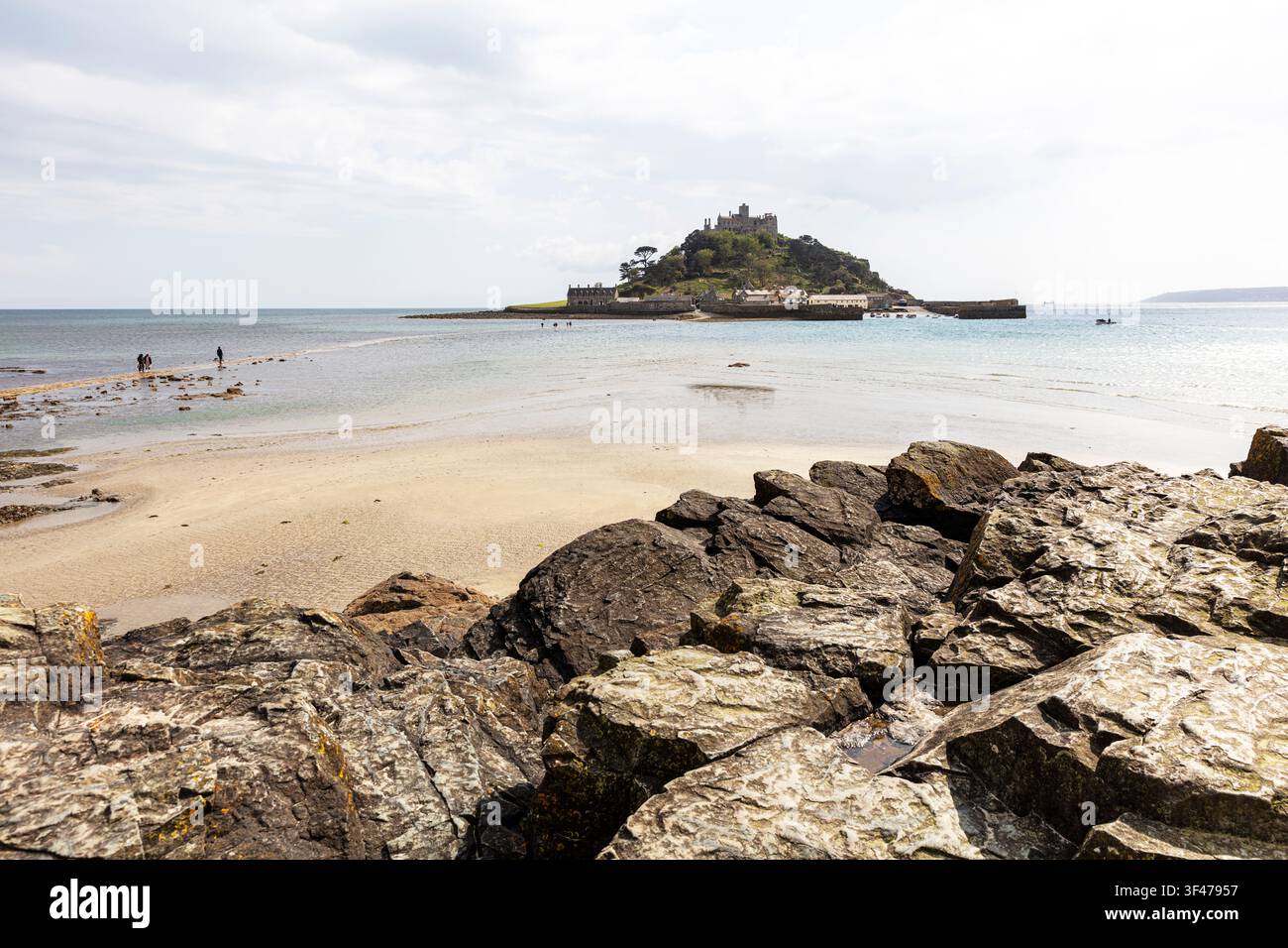 Monte Sant'Michael in Cornovaglia, con grandi rocce erose in primo piano che conducono verso il barriera di marea e l'isola. Il castello storico si erge Foto Stock