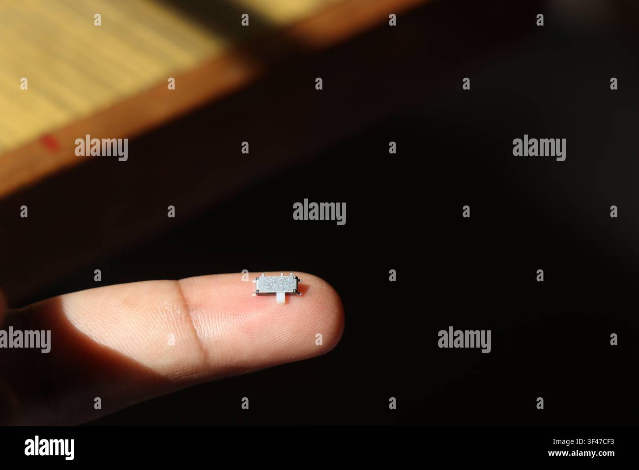 Interruttore a scorrimento micro SMD di tipo orizzontale utilizzato nei circuiti elettronici e nelle schede a circuito stampato tenuto sulla punta del dito Foto Stock