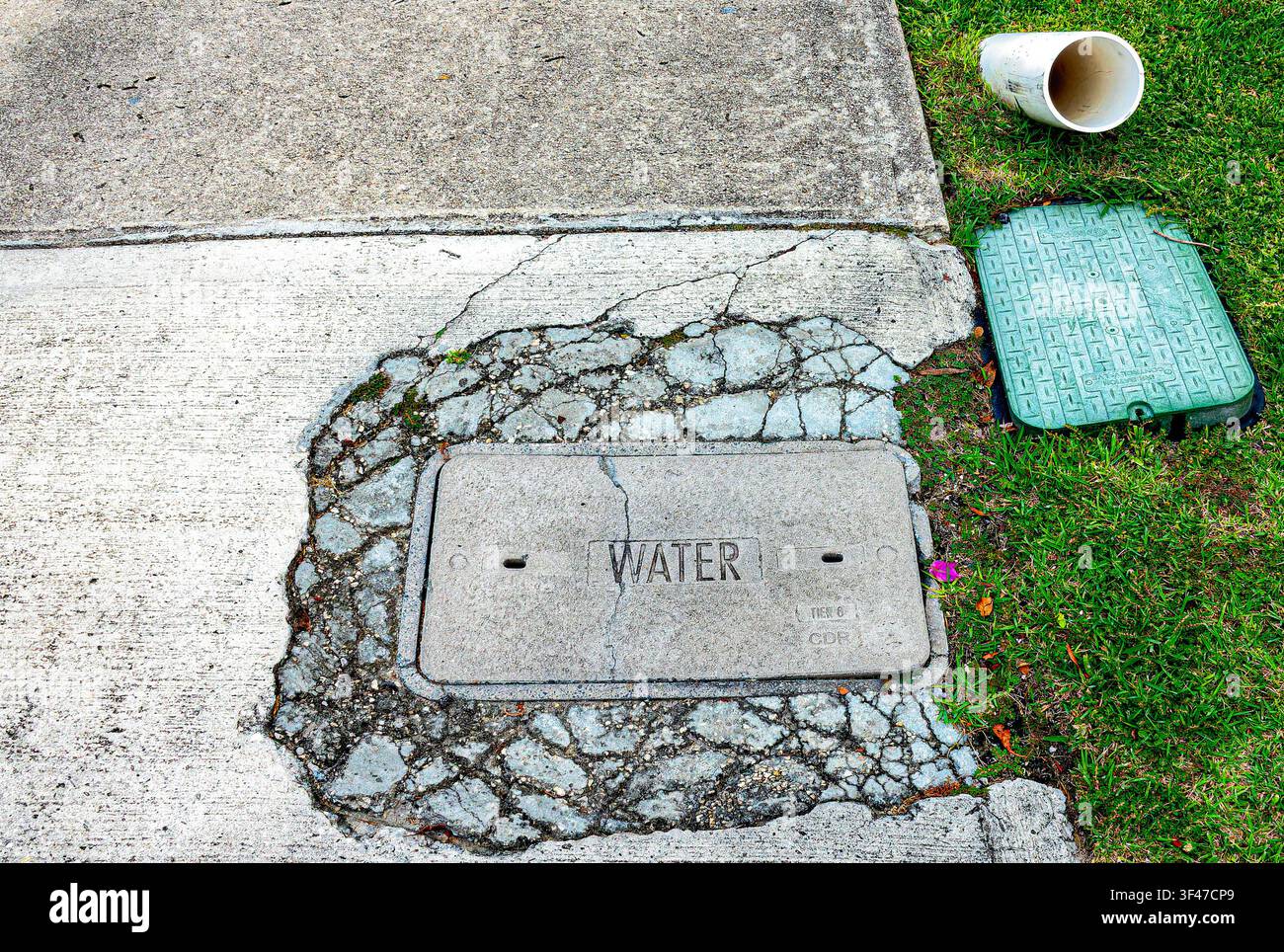 Un pannello di accesso per servizi, in particolare una copertura del contatore dell'acqua, incastonato in un marciapiede. Foto Stock