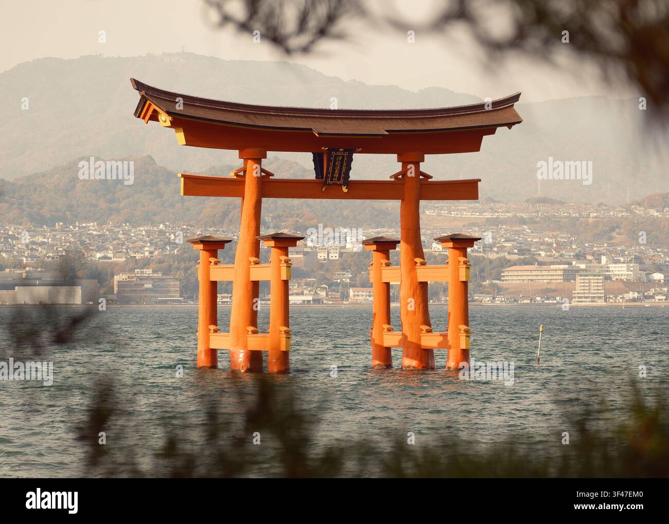 Vista chiara del pomeriggio sull'acqua della baia costiera verso l'iconica grande porta galleggiante torii del Santuario di Itsukushima, Hiroshima, Giappone. Foto Stock