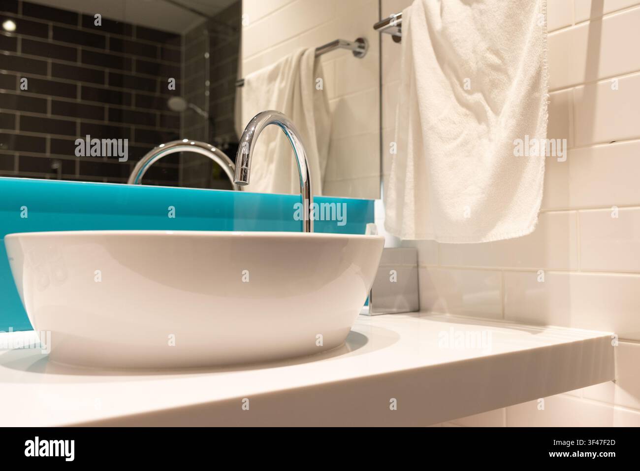 Asciugamani puliti appesi a un lavandino in un bagno moderno con accenti blu e uno specchio Foto Stock