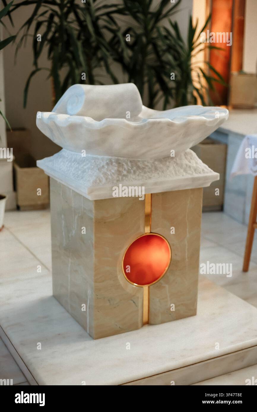 Battezzale in marmo ornato all'interno della chiesa. Allestimento del sacramento cristiano ortodosso o cattolico, recipiente per l'acqua santa per il battesimo infantile Foto Stock
