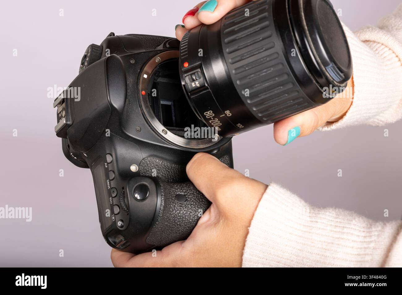 Mani che fissano un obiettivo della fotocamera a una fotocamera digitale DSLR Foto Stock