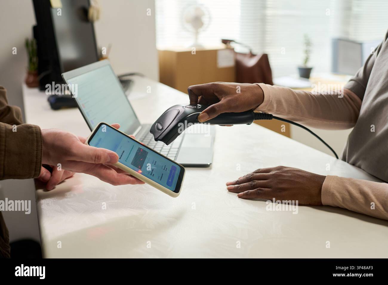 Donna nera che scansiona lo smartphone per il codice a barre di ritiro Foto Stock