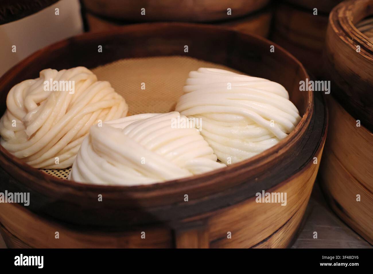 Gli involtini cotti a vapore cinesi - rotoli di fiori (Hua Juan) sono disposti in un vaporetto di bambù servito in un ristorante a Changsha City, provincia di Hunan in Cina Foto Stock