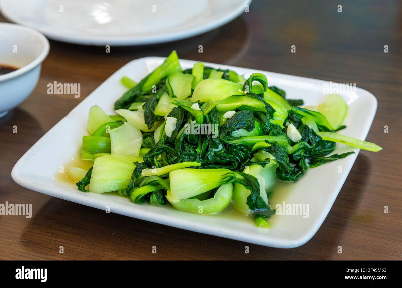 Pak choi fresco saltato con aglio, un classico contorno vegetale asiatico delizioso e salutare, servito in un ristorante Foto Stock