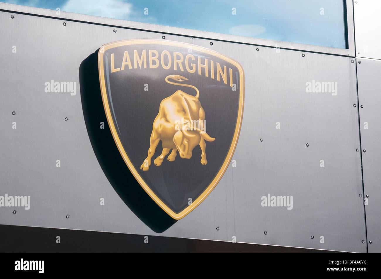 Grancia, Ticino, Svizzera – 15 giugno 2026: Primo piano ad angolazione bassa del logo ufficiale Automobili Lamborghini, toro dorato furioso, sulla facciata del concessionario Foto Stock